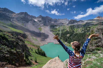 Woman hiker wearing patriotic clothing enjoys the view at Blue Lakes Trail in Colorado