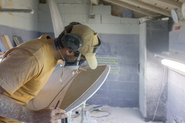 Surfboard making, Shaper measuring blank surfboard with a template.Craftsman at work