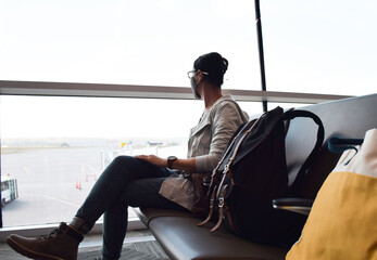 Woman in face mask sitting at airport waiting for her flight