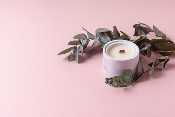 Soy wax candle and eucalyptus on pink background. Space for text