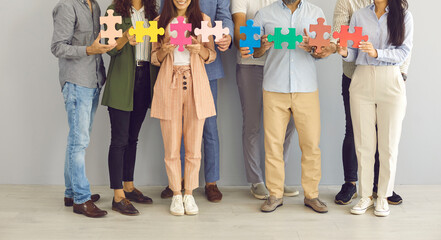 Team of creative business people making chain of jigsaw puzzle parts. Cropped group studio shot of...