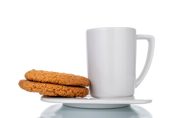 Obraz na płótnie Canvas Two fresh oatmeal cookies on a white ceramic saucer with a cup, close-up, isolated on white.