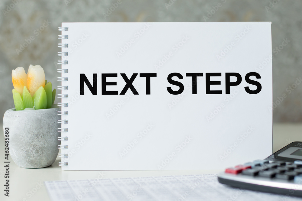Poster next steps text on a notebook on an office desk