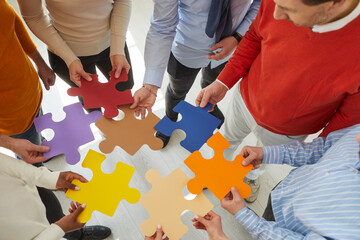 Team of creative people and business colleagues meeting in office and joining colorful jigsaw...
