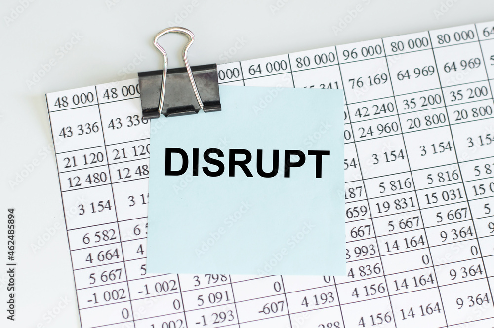 Poster a card with the text disrupt on the table with a clip attached by a black clip to the financial stat