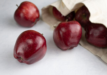 Red chief apples rolled out of a linen eco bag on a white surface
