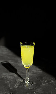 Limoncello liqueur or poncha drink with copy space on black surface in bright sunlight