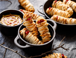 Mummy dogs made of sausages and puff pastry on a black background, close up view. Halloween funny food idea for  party.  