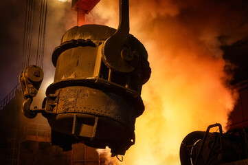 A metallurgical ladle filled with molten metal bucket is suspended on a special crane beam