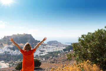 A blonde woman looks at the panorama of Lindos on the island of Rhodes, Greece
