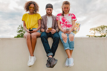 happy young company of smiling friends sitting in park