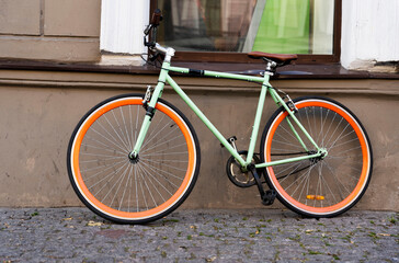 Fototapeta na wymiar A city bike parked against the wall of a cafe in the city, Cycling to work, a stylish bike in an urban environment