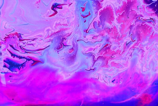 Abstract background of blue-pink marble. Acrylic paint mixes freely and creates an interesting pattern. Bright saturated shades. Background for the cover of a laptop, laptop.