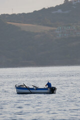 Fototapeta na wymiar Fisherman small boat at 400mm with mountains in the backgorund