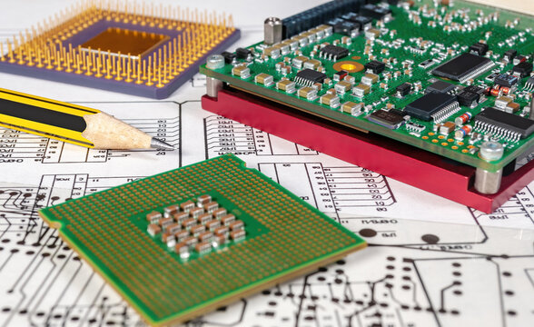 Electronic board, pen, and processors  on background of  schematic circuit diagram and a photomask for manufacture of printed circuit boards. Concept for development and design of electronic devices.