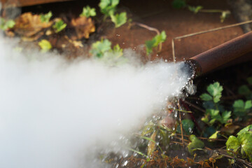 Ejection of hot water and steam from an iron pipe.