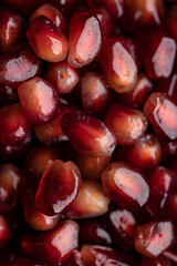 A lot of beautiful red pomegranate seeds in a black bowl on a white background