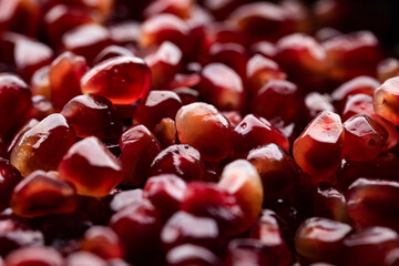 A lot of beautiful red pomegranate seeds in a black bowl on a white background