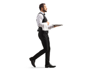 Full length profile shot of a waiter carrying a silver tray and walking
