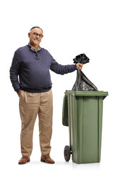 Mature man standing next to a waste bin and throwing a plastic bag inside
