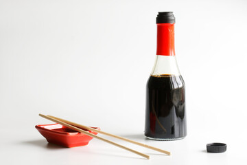 Red Japanese sauce bowl - seyuzaru, sticks - varibashi and a glass bottle with soy sauce on a white background