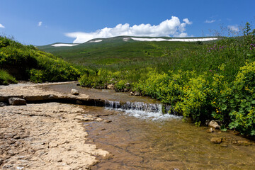 A park area along the bed of a mountain river, walks on a sunny summer day, places to communicate...