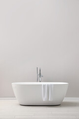 Naklejka na ściany i meble Modern ceramic bathtub with towel near light wall indoors