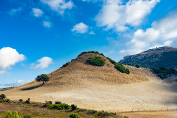 Stunning view of a pyramid shaped hill with a blue, cloudy sky. Sardinia, Italy.