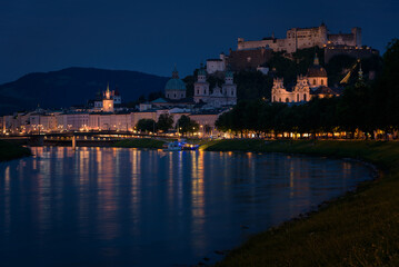 Obraz na płótnie Canvas Panoramic view of illuminated Salzburg skyline with river Salzach in summertime at night, Austria