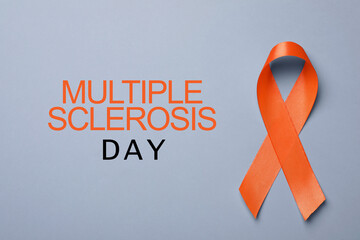 Multiple Sclerosis Awareness Day. Orange ribbon on grey background, top view