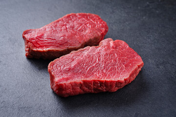 Raw dry aged bison beef rump steaks offered as close-up on black background with copy space