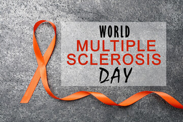 Multiple Sclerosis Awareness Day. Orange ribbon on grey background, top view