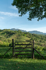 Fototapeta na wymiar Wooden fence and green tree leaves with blue sky. Tamesis, Antioquia, Colombia.