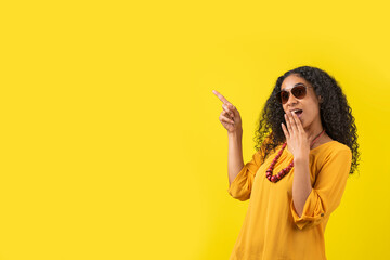 Mujer afroamericana asombrada señalando a un lado en un fondo amarillo