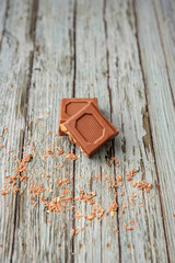 Two pieces of chocolate with peanuts stacked facing each other on a wooden background