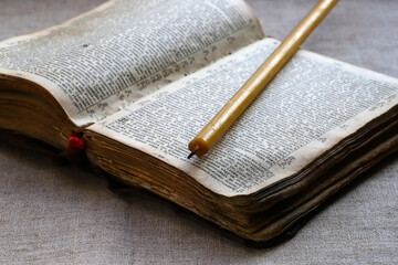 Wax candle on an old open bible. Religious text in Old Slavonic, church language. The concept of...