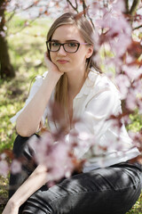 girl sitting under a blossoming tree in the park © ms16_photo