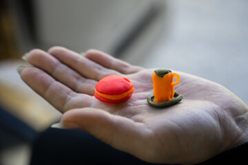 Decorative cup and cookies made of plasticine on a child's hand