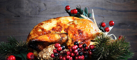 Christmas holiday web banner. Scrumptious roast turkey chicken on platter with festive decorations for Thanksgiving or Christmas lunch, against dark recycled wood background.