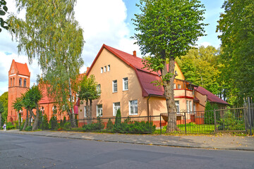 Fototapeta na wymiar A German-built residential building (1910) and a fragment of the building of the church of the suburb of Ponart. Marshal Novikov Street, Kaliningrad