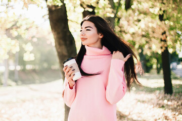 Beautiful woman drink coffee and walking in the park.