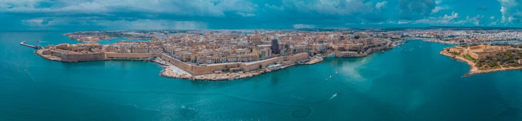 Aerial drone panorama or cityscape of Valetta, capital of malta on a sunny day with storm clouds in the background. - obrazy, fototapety, plakaty