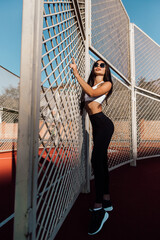 Beautiful fitness woman in sportswear posing near grid.