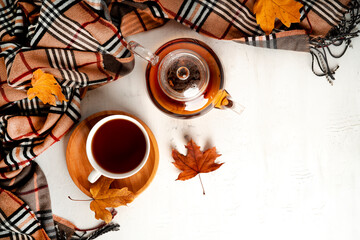 Autumn composition. A cup of tea and teapot, scarf, autumn leaves. Flat lay, top view, copy space