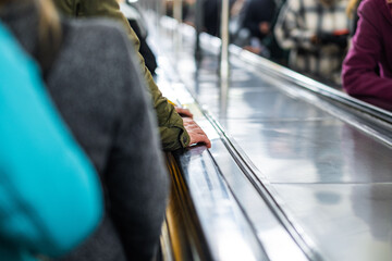 People hold hands on the dirty handrails of the escalator in the subway, close-up