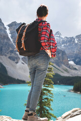 Woman with backpack standing looking at beautiful lake and mountains