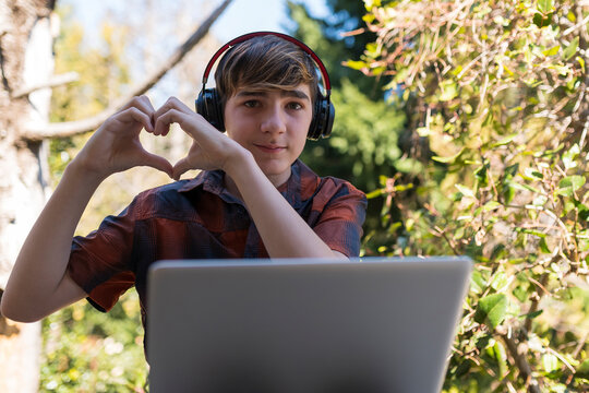 Joven enviando saludo coraz&oacute;n  a sus padres por medio de la virtualidad y la distancia en tiempos de pandemia. 
