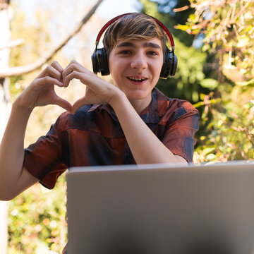 Joven enviando saludo coraz&oacute;n  a sus padres por medio de la virtualidad y la distancia en tiempos de pandemia. 