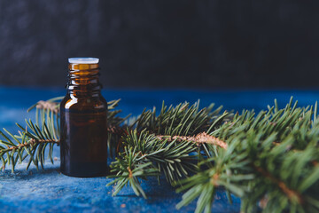 Bottle of coniferous essential oil on dark background