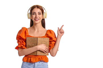 Young woman with headphones and book pointing at something on white background